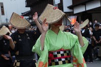 People wearing a woven hat and traditional clothes dance to the music of 