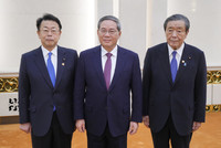 Komeito Secretary-General Makoto Nishida (left), Chinese Premier Li Qiang (center) and LDP Secretary-General Hiroshi Moriyama (right) pose for a photo at the Great Hall of the People in Beijing on Wednesday. (Pool photo)