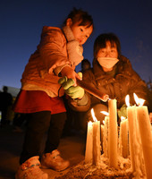 A parent and a child light a candle at an event in Itami, Hyogo Prefecture, on Thursday to remember the victims of a powerful earthquake that struck on Jan. 17, 1995.