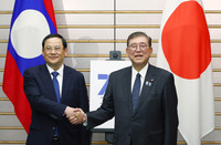 Japanese Prime Minister Shigeru Ishiba (right) and Lao Prime Minister Sonexay Siphandone shake hands in Tokyo on Tuesday.