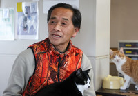 Holding one of the cats he cares for, Toru Akama speaks during an interview in the town of Namie, Fukushima Prefecture, on Feb. 1.