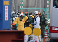 Police officers and firefighters prepare to enter the sewage pipe Thursday morning at the site of a road collapse in Yashio, Saitama Prefecture, in late January.