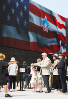 U.S. Ambassador to Japan George Glass (third from right) welcomes visitors in front of the U.S. pavilion at the Osaka Expo on Friday.