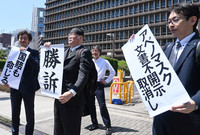 Plaintiff Professor Hiroshi Kamiwaki (center) and others hold up a paper with