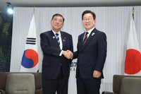 Japanese Prime Minister Shigeru Ishiba (left) and South Korean President Lee Jae-myung shake hands before their meeting in Kananaskis, Canada, on Tuesday.