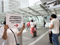 A person directing people to Nissan's general meeting of shareholders with a signboard in Yokohama, Kanagawa Prefecture, on Tuesday