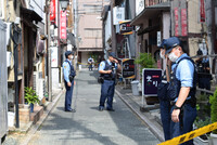 Police officers investigate the area around the scene where two people, including a girls' bar manager, were stabbed to death by a man in Hamamatsu, Shizuoka Prefecture, on Sunday.