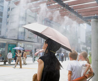 People cool off under a mist device in Tokyo's Chuo Ward on Monday.