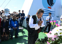 A former Northern Territories resident prays for ancestors aboard the Etopirika ship Sunday. (Pool photo)