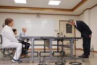 Hisaaki Ikeuchi (right), chief of Shiga prefectural police, apologizes to former assistant nurse Mika Nishiyama (front left) in Hikone, Shiga Prefecture, on Thursday.