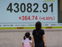 A monitor at a securities company in Tokyo's Chuo Ward shows Japan's benchmark Nikkei 225 stock average topping 43,000 for the first time ever on Wednesday morning.