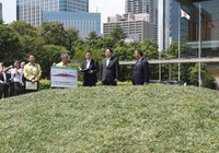 Japanese Chief Cabinet Secretary Yoshimasa Hayashi (second from right) and others look at how soil removed in decontamination work in Fukushima Prefecture is used at the prime minister's office in Tokyo on July 22.