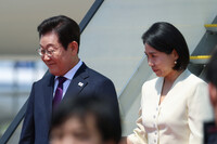 South Korean President Lee Jae-myung (left) and his wife, Kim Hye-kyung, arrive at Haneda Airport in Tokyo Saturday morning.