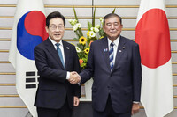 Japanese Prime Minister Shigeru Ishiba (right) and South Korean President Lee Jae-myung shake hands before their meeting at the Japanese prime minister's office in Tokyo on Saturday. (Pool photo)